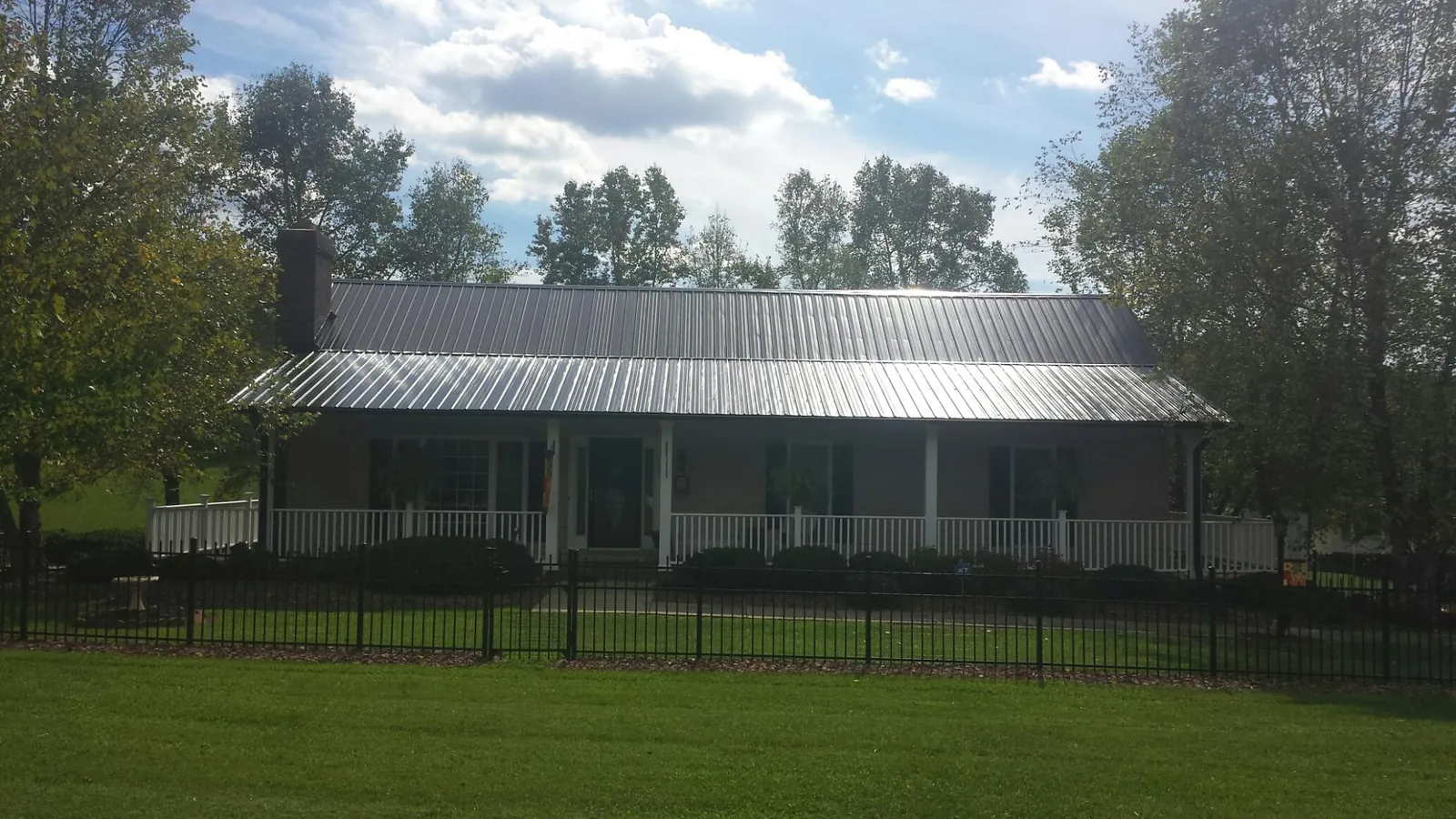 Gray metal roof on a brick ranch with a full width front porch — Gutter Guard Installation work by our crew in Chelsea