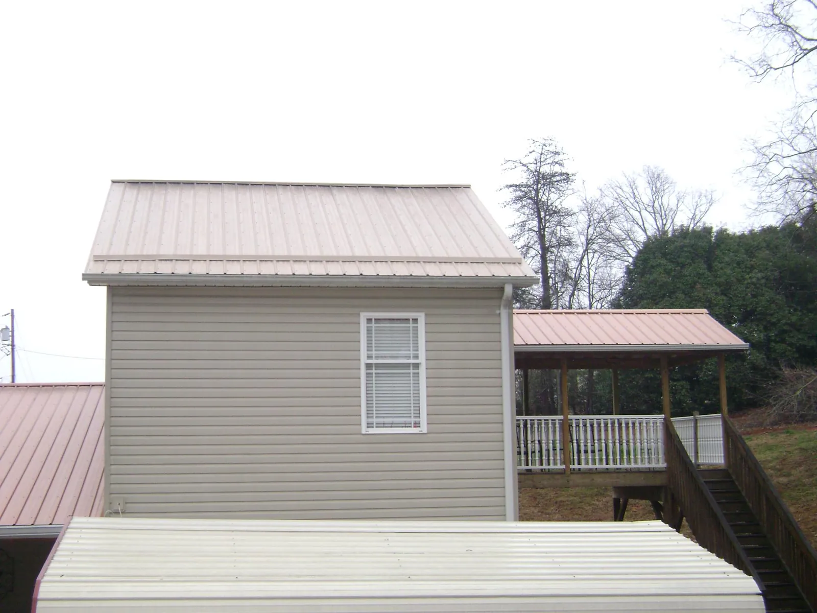 Tan metal roofs on a two story addition and attached porch, from a Roof Replacement job in Chelsea